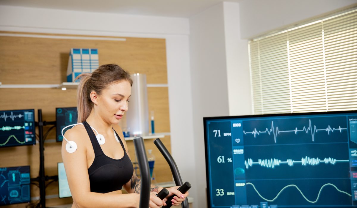 Female athlete who makes a physical effort on the stepper and has electrodes attached to it and the results are seen on the screen. Sports laboratory